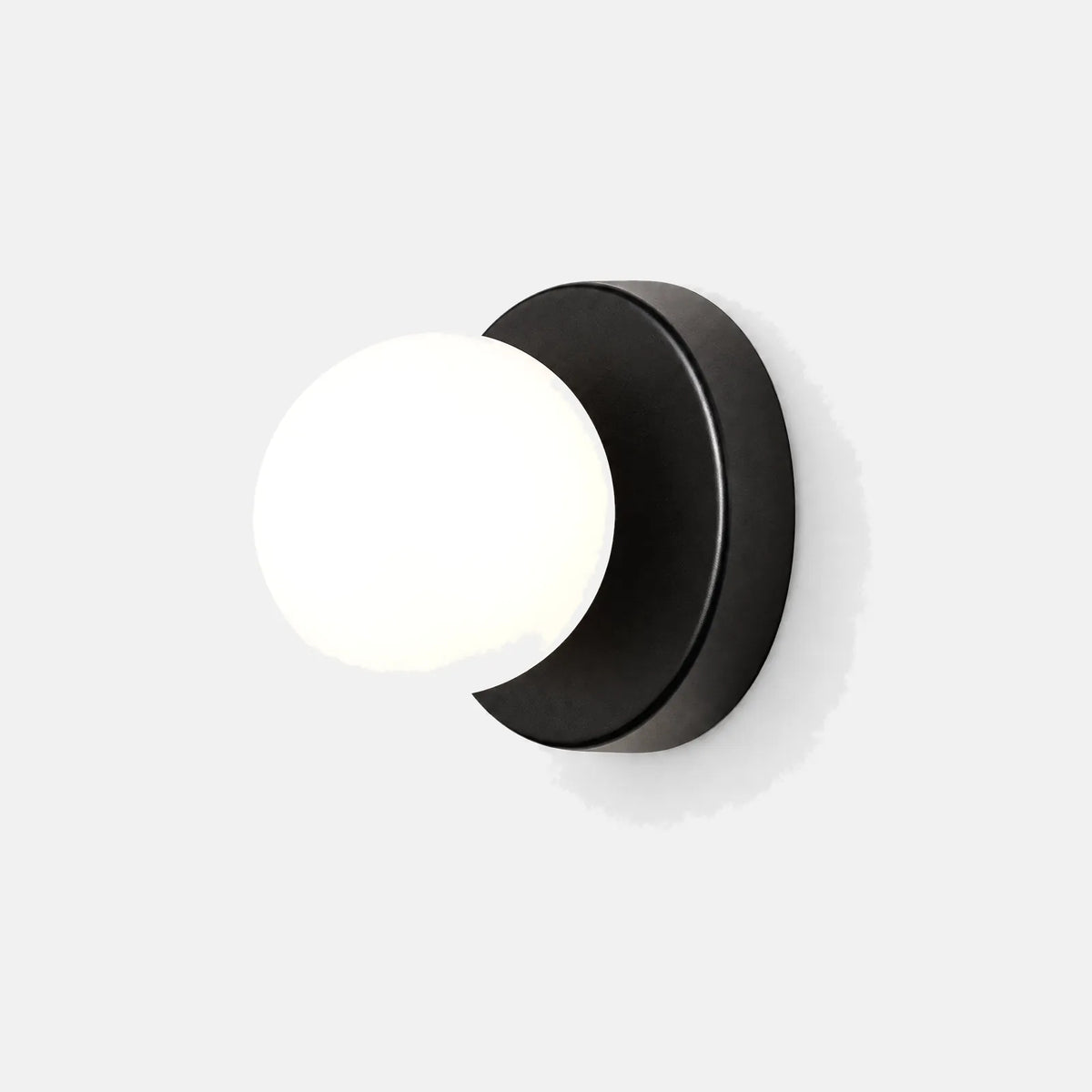 Applique boule Olia, disque noir et globe en verre opalin, sur fond uni
