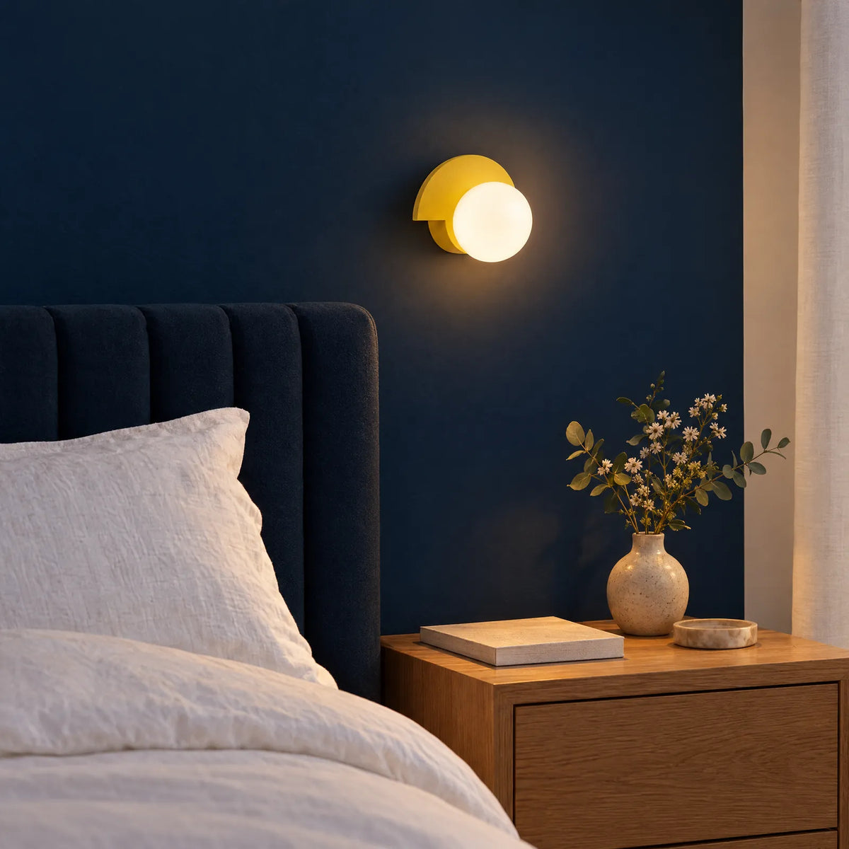 Applique Polux jaune allumée en liseuse sur un mur bleu nuit