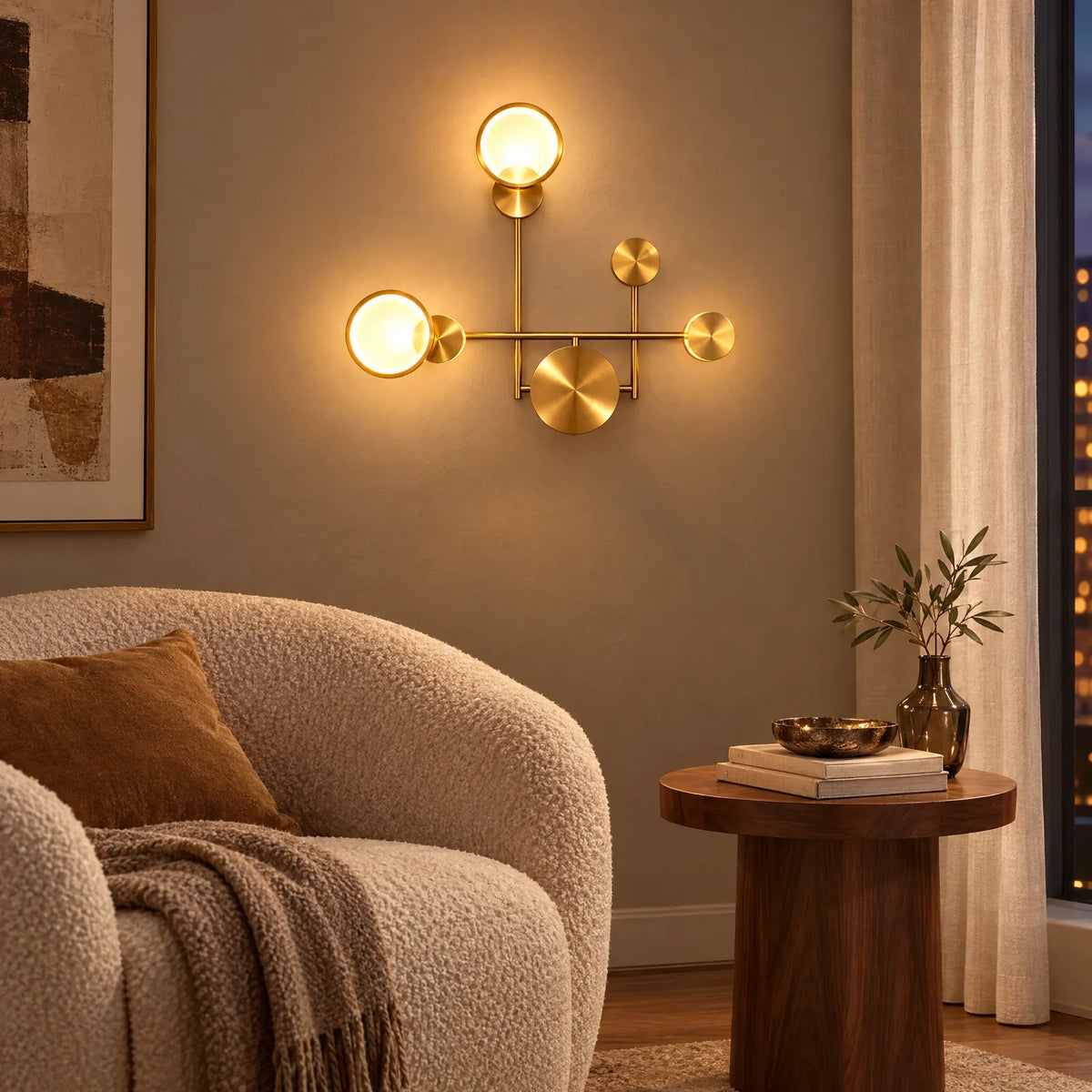 Applique LED Yoka dorée allumée au-dessus d'un fauteuil bouclette
