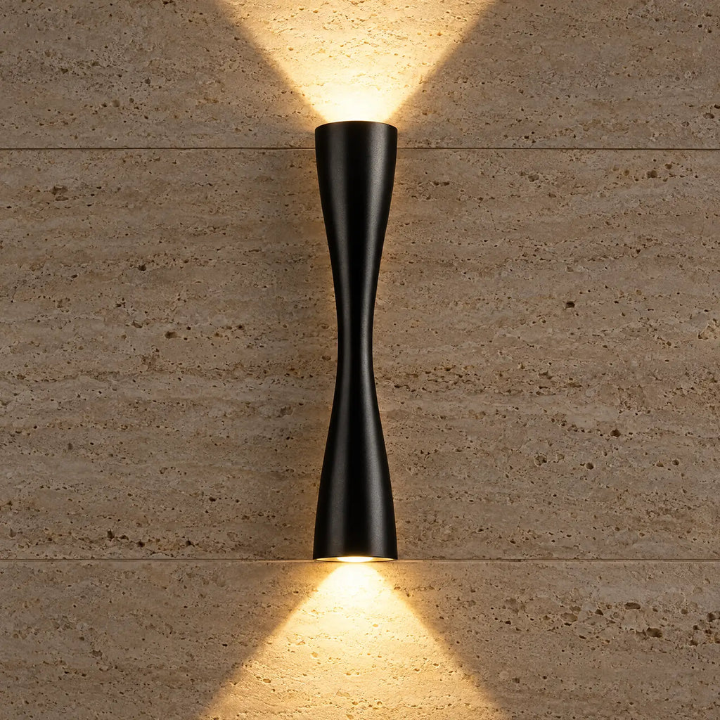 Faisceaux lumineux haut et bas de l'applique Caria noire sur un mur en travertin