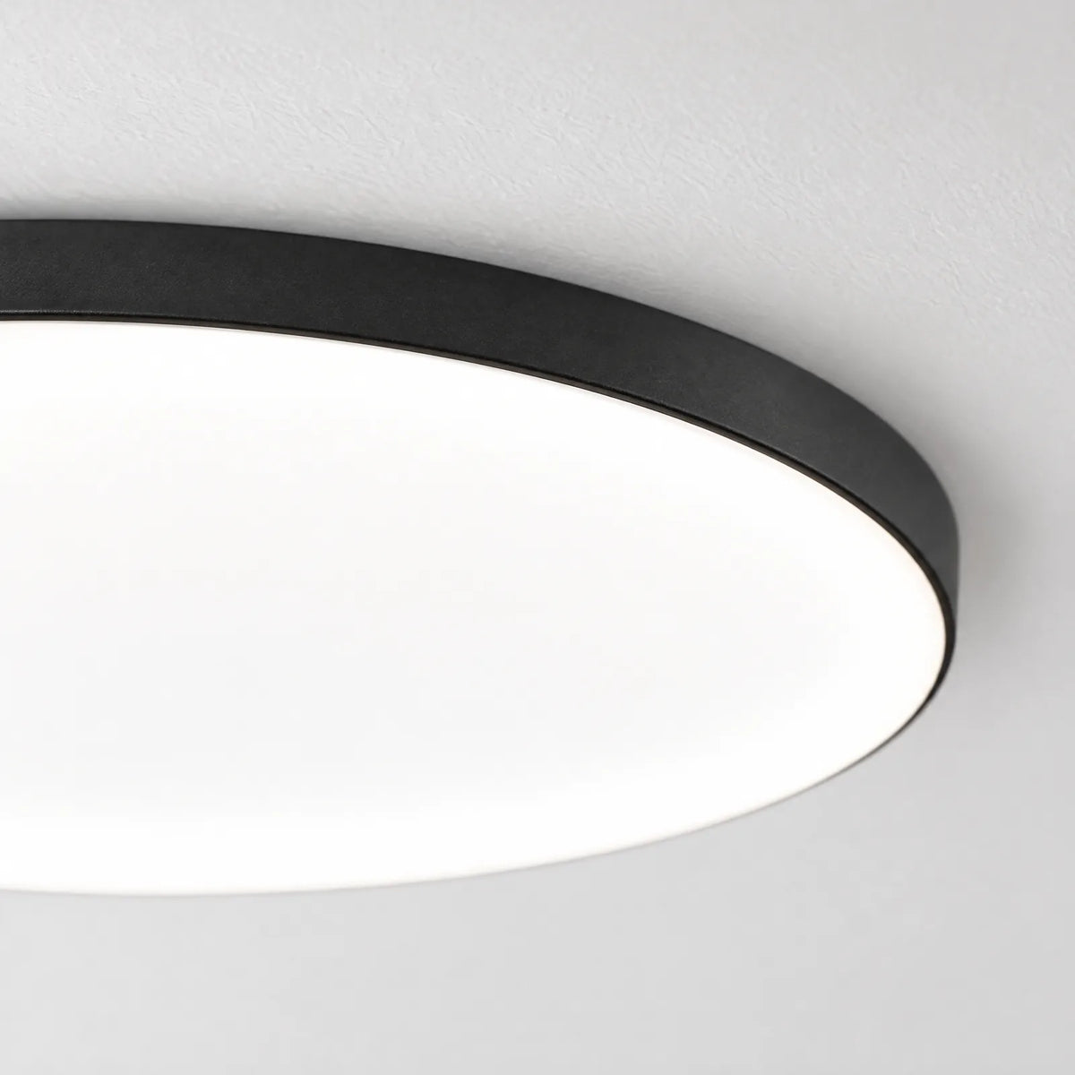 Détail du contour noir et du diffuseur allumé du plafonnier Ify