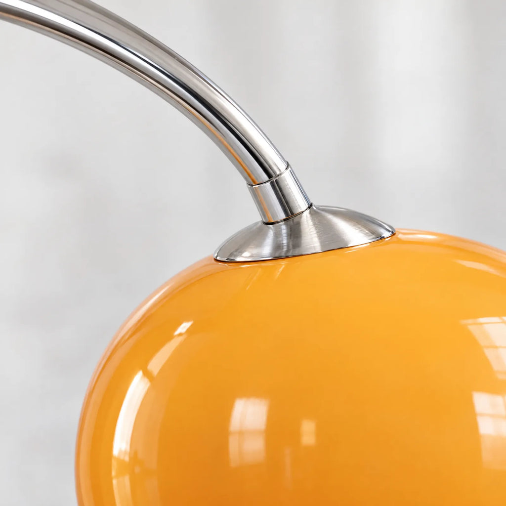 Détail de la fixation chromée et de l'abat-jour dôme orange du lampadaire Yva