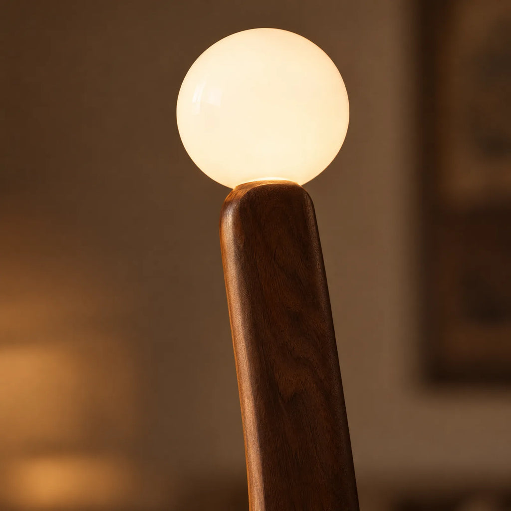 Détail du globe en verre opalin allumé sur le bois de noyer du lampadaire Solad