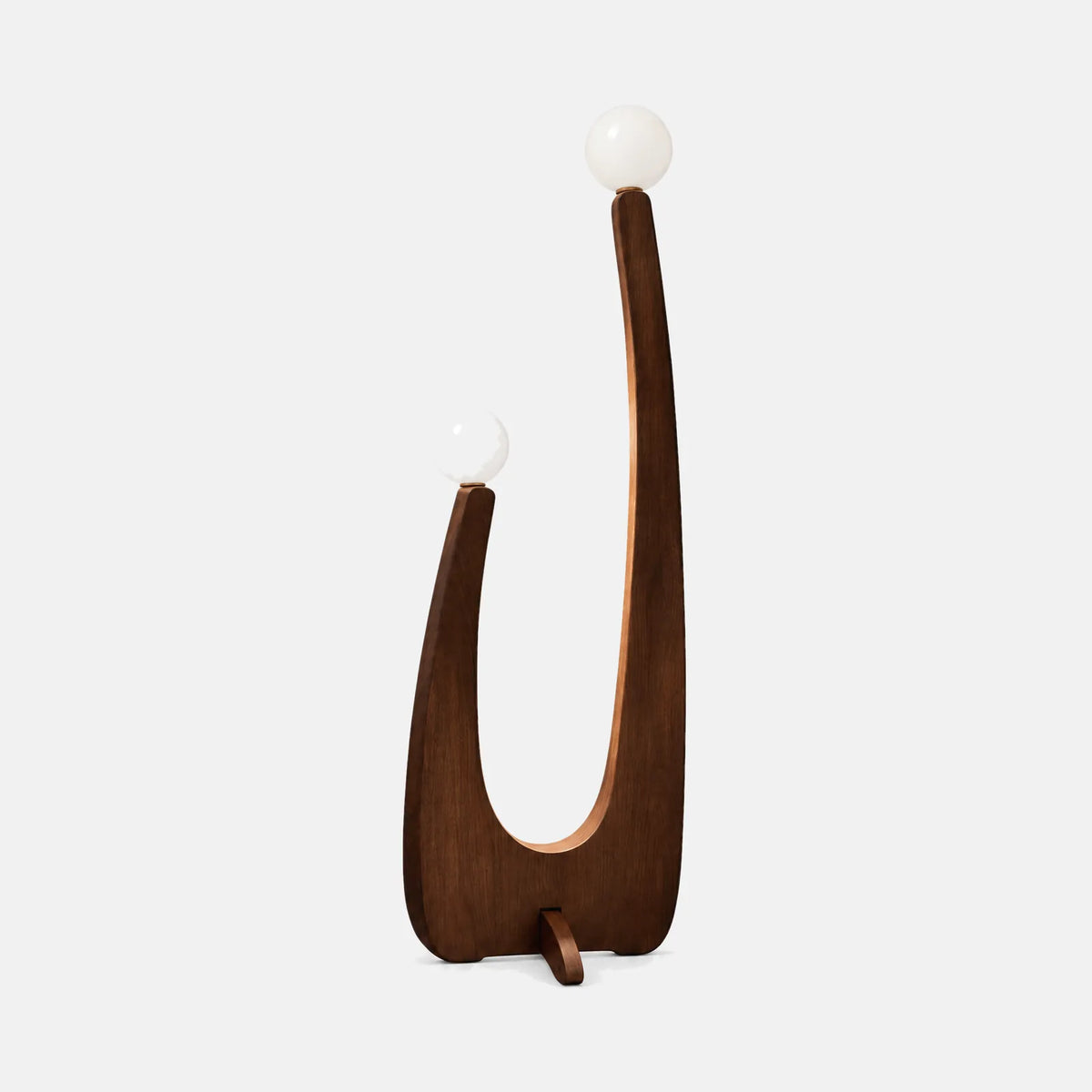 Lampadaire sculptural Solad en noyer avec deux globes en verre opalin, sur fond uni