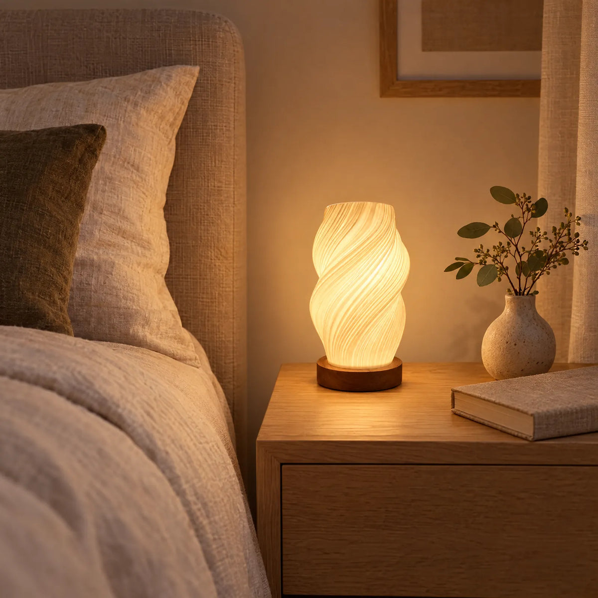 Lampe torsadée Yva allumée sur une table de chevet