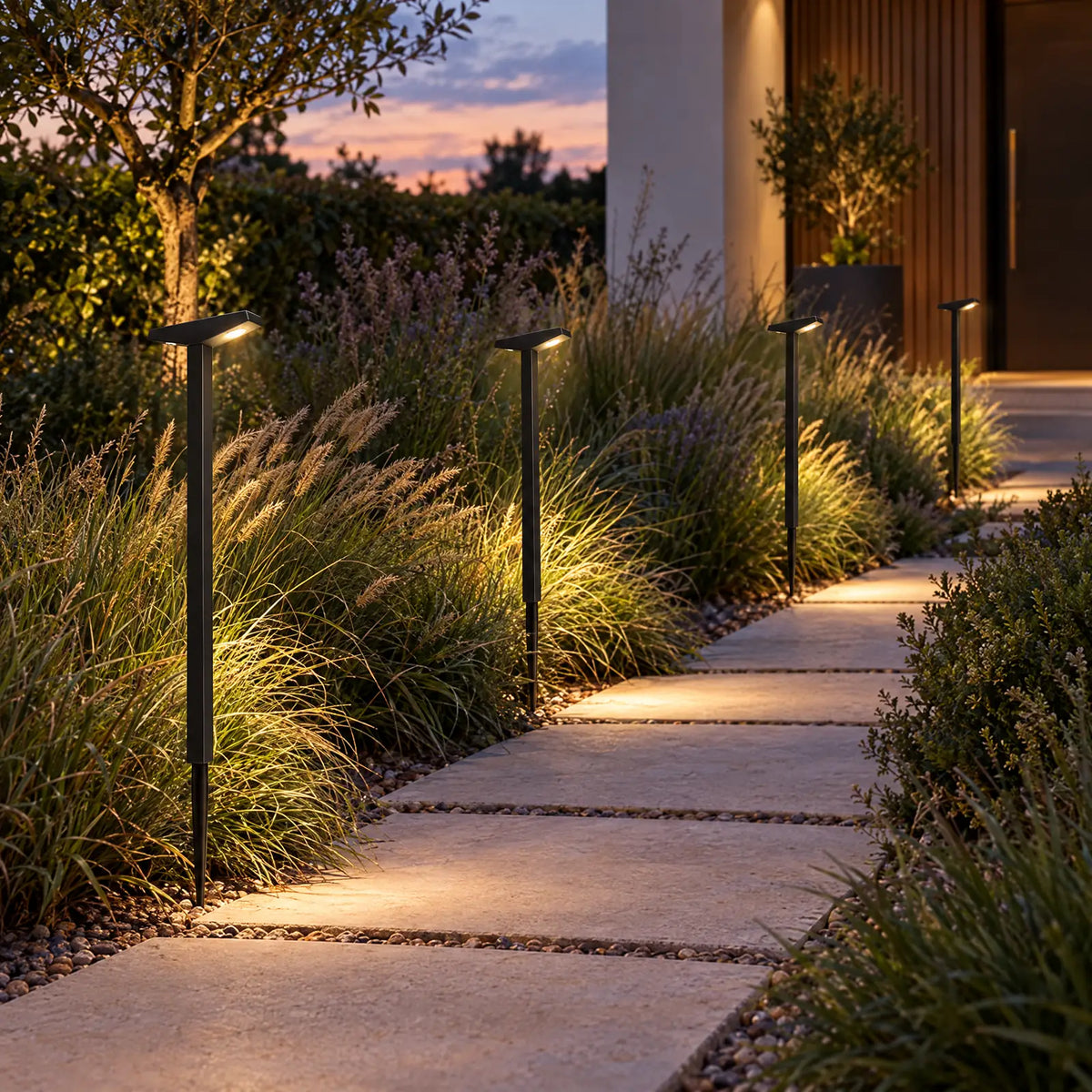Bornes solaires Lumo allumées le long d'une allée de jardin