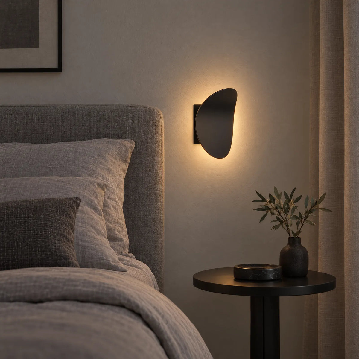 Applique LED Bolio noire allumée à côté d'un lit