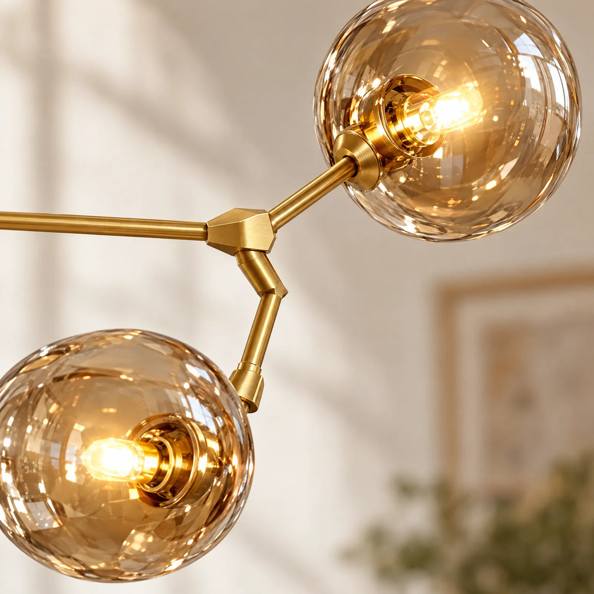 Détail des globes en verre ambré et des bras dorés du lustre Hora