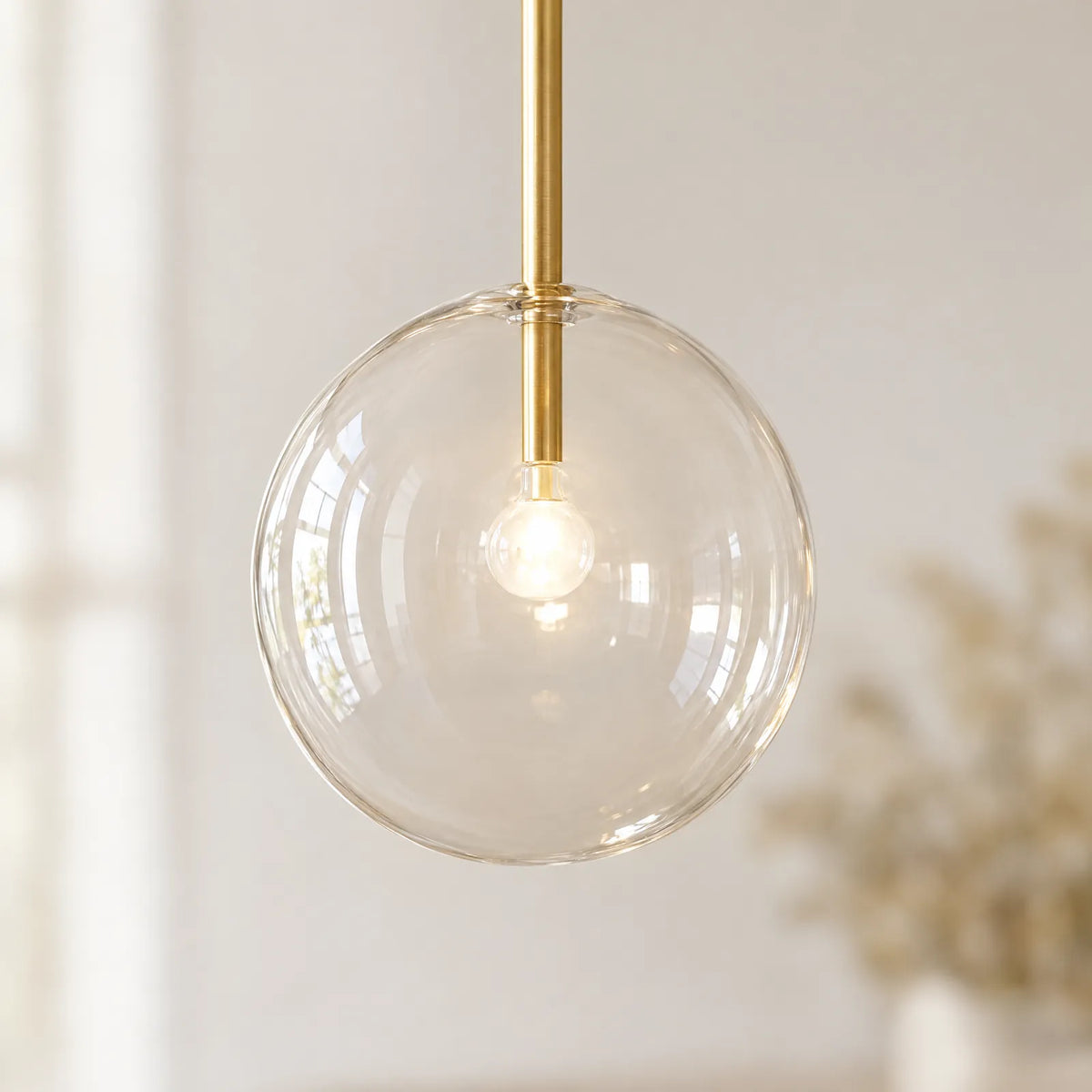 Détail du globe en verre soufflé transparent et du tube en laiton brossé de la suspension Xana