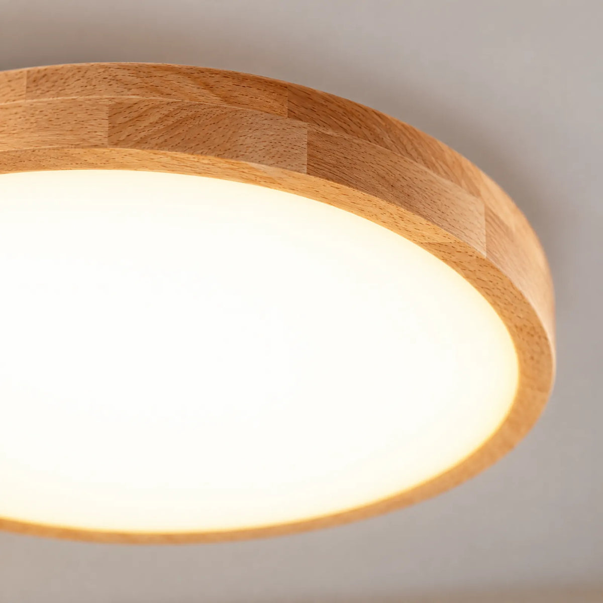Détail du contour en bois de hêtre et du diffuseur allumé du plafonnier Melo