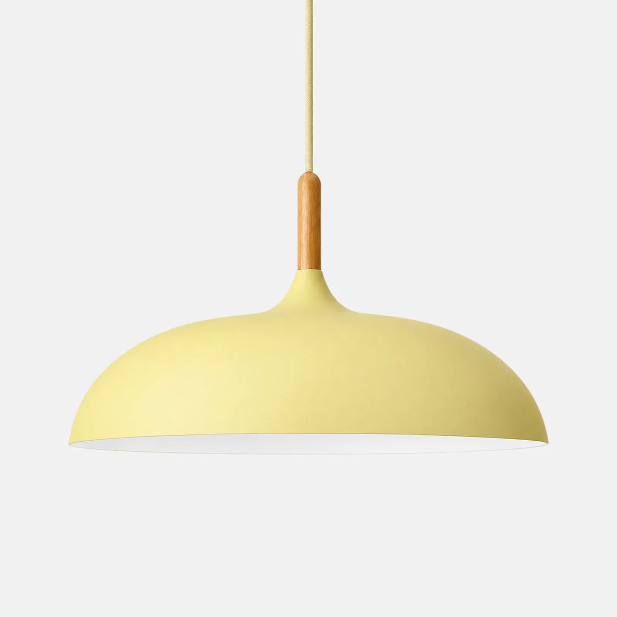Plafonnier suspendu design Rico jaune pastel, dôme en aluminium et col en bois, sur fond uni