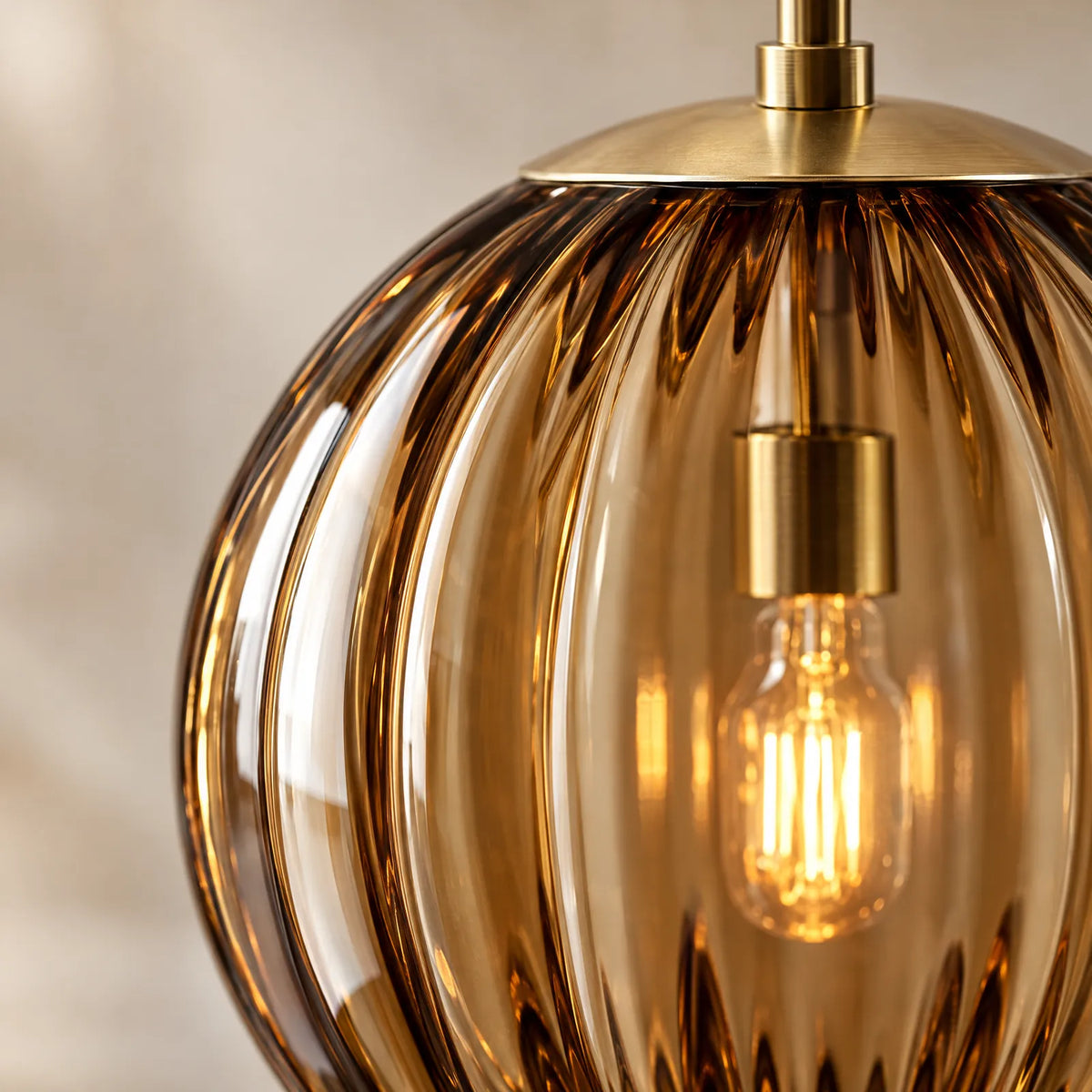 Détail du verre côtelé ambré et de l'ampoule à filament de la suspension Tara