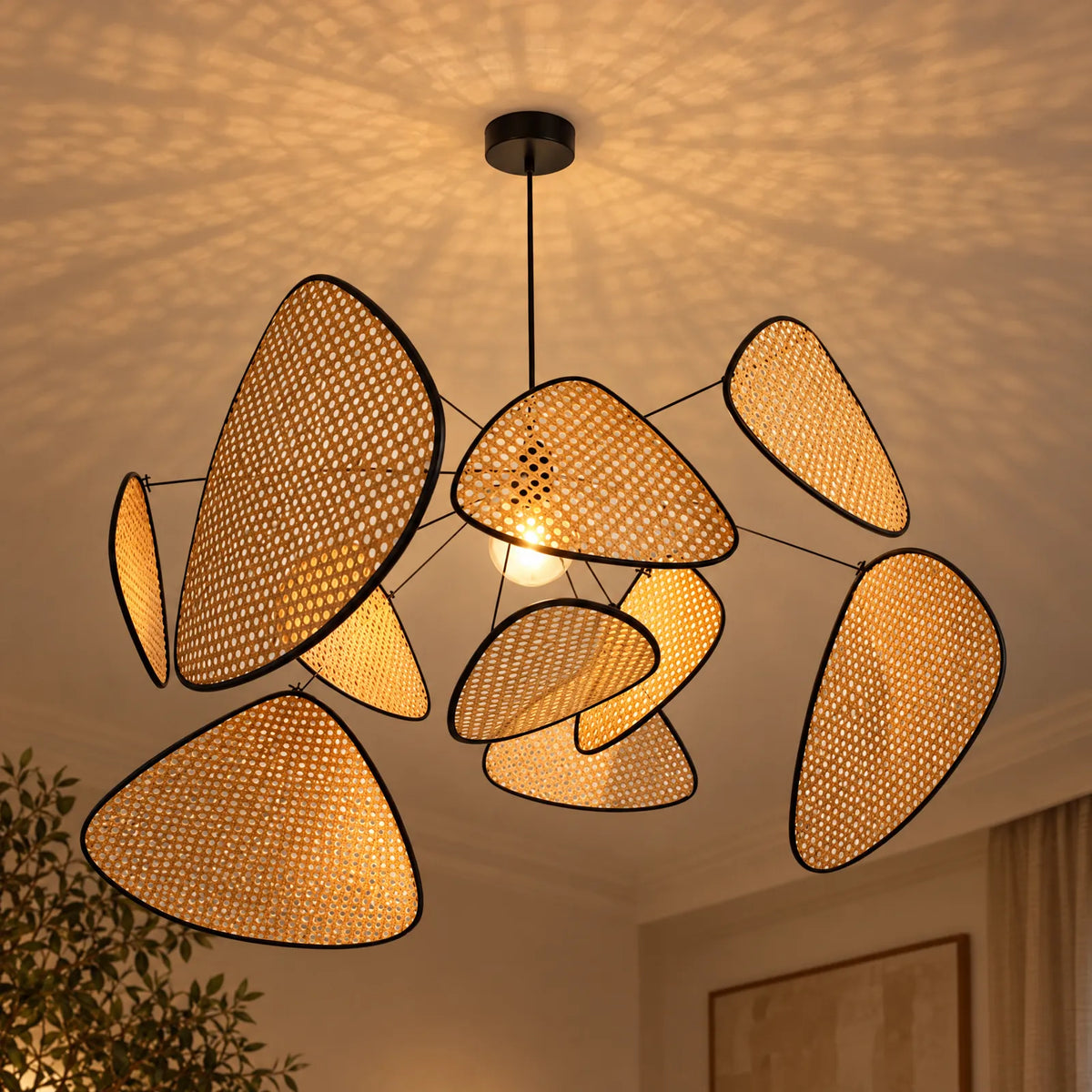Lustre rotin Iva allumé projetant le motif du cannage au plafond
